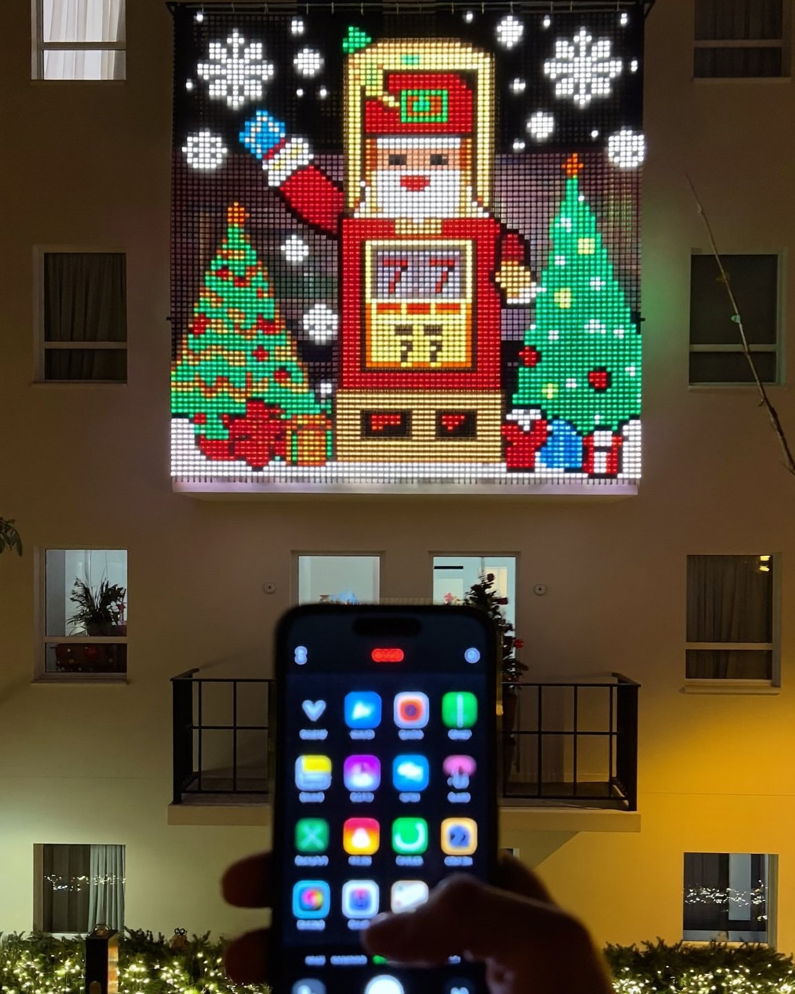 MerryMarquee lit up at night with Santa and a slot machine, phone app in hand